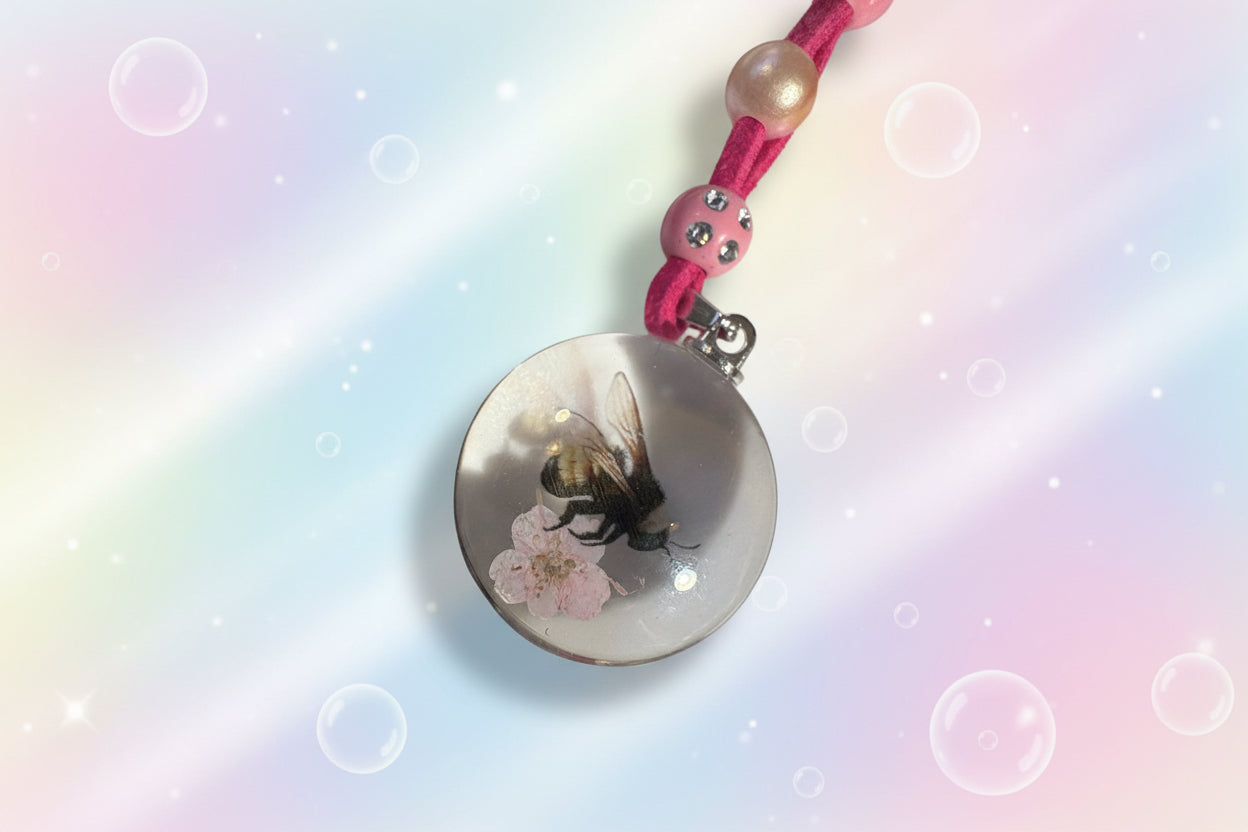 This is a close up of the resin pendant showing the holographic image of a bee on a cherry blossom