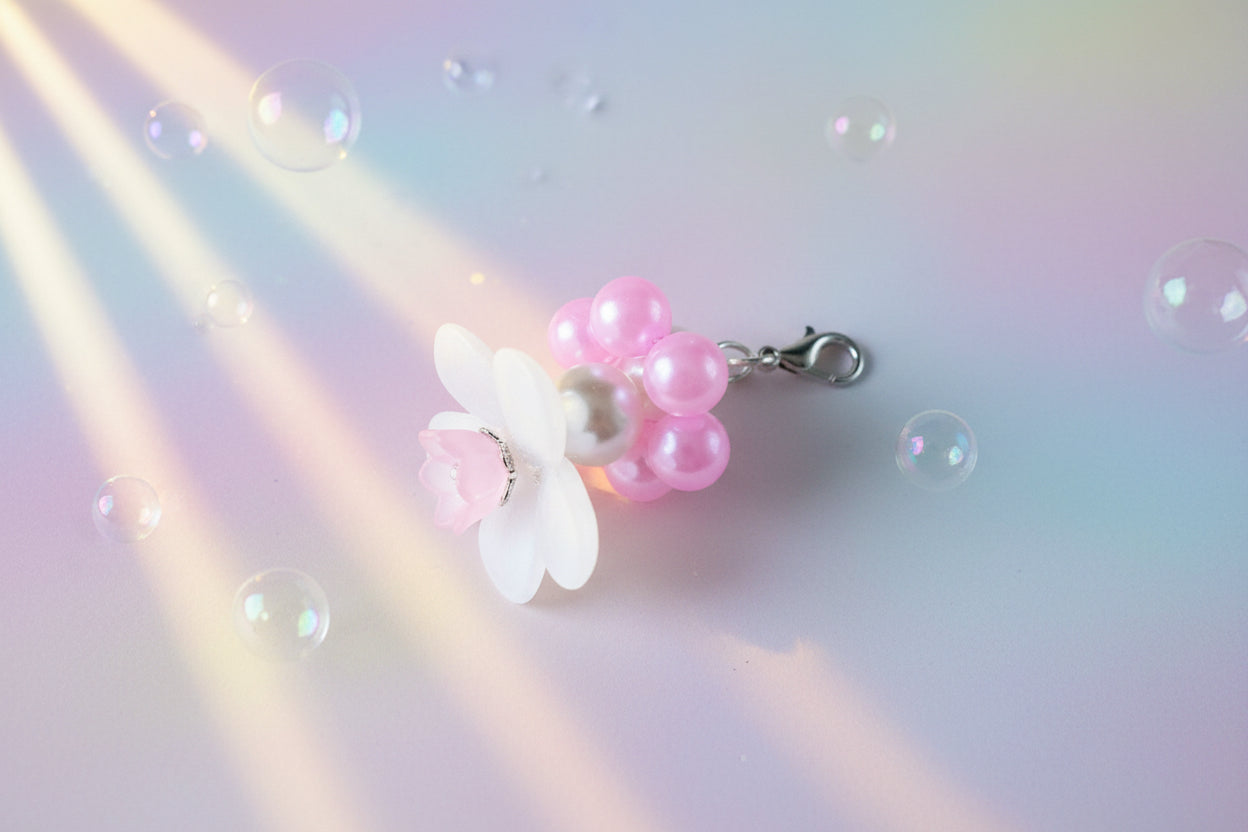 A stunning white flower bead takes centre stage, encircled by shimmering light pink pearlescent beads that create a mesmerising spinning effect. The soothing tactile motion helps with focus and stress relief while looking absolutely magical.