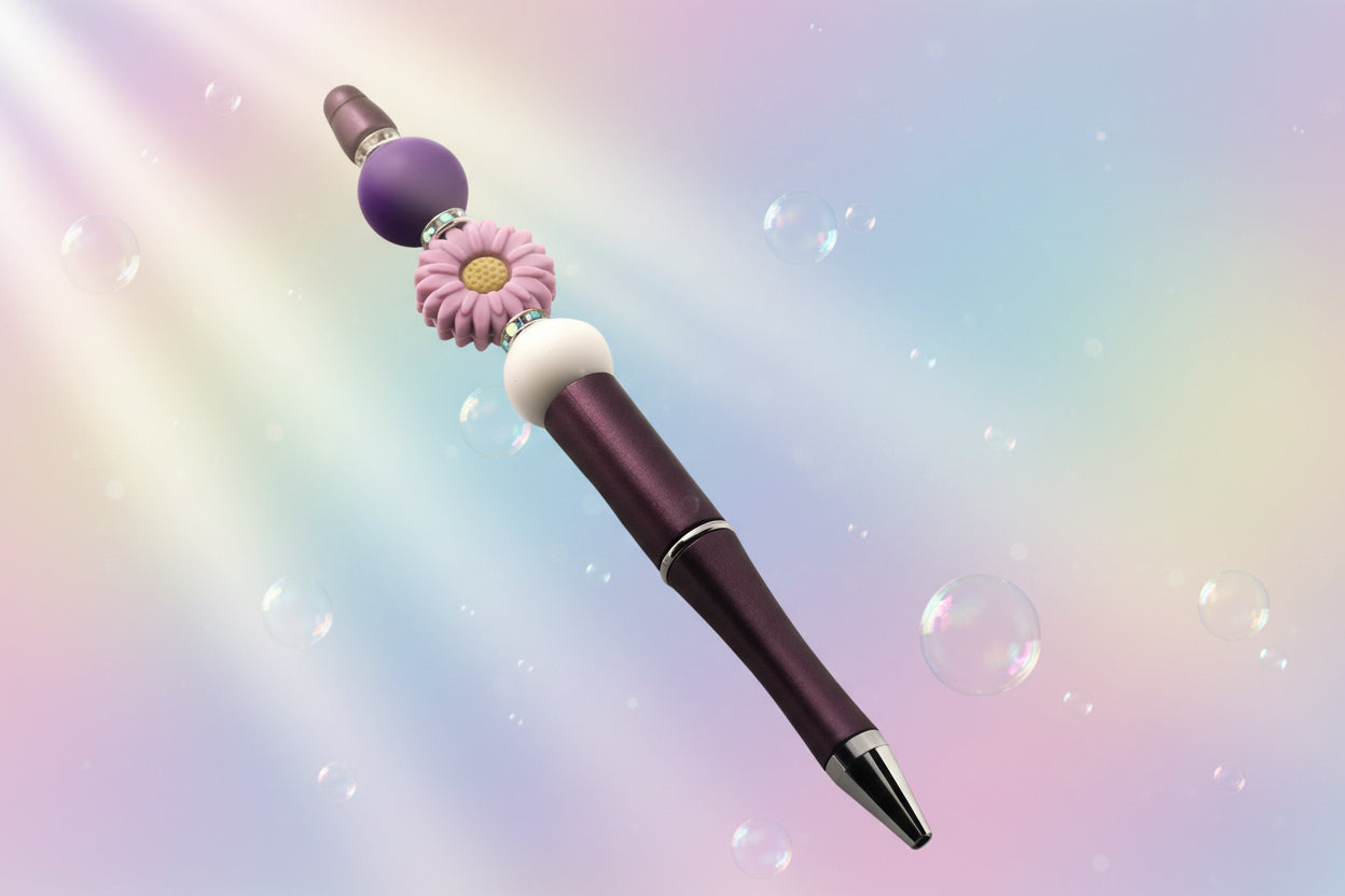 A purple metallic pen with a purple daisy shaped bead, a purple round bead, a white bead and sparkly Rondelle.