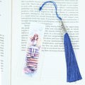 Mark your place in style! This cheerful acrylic bookmark features a delightful design of a young girl sitting on a tower of books and celebrating the joy of reading.