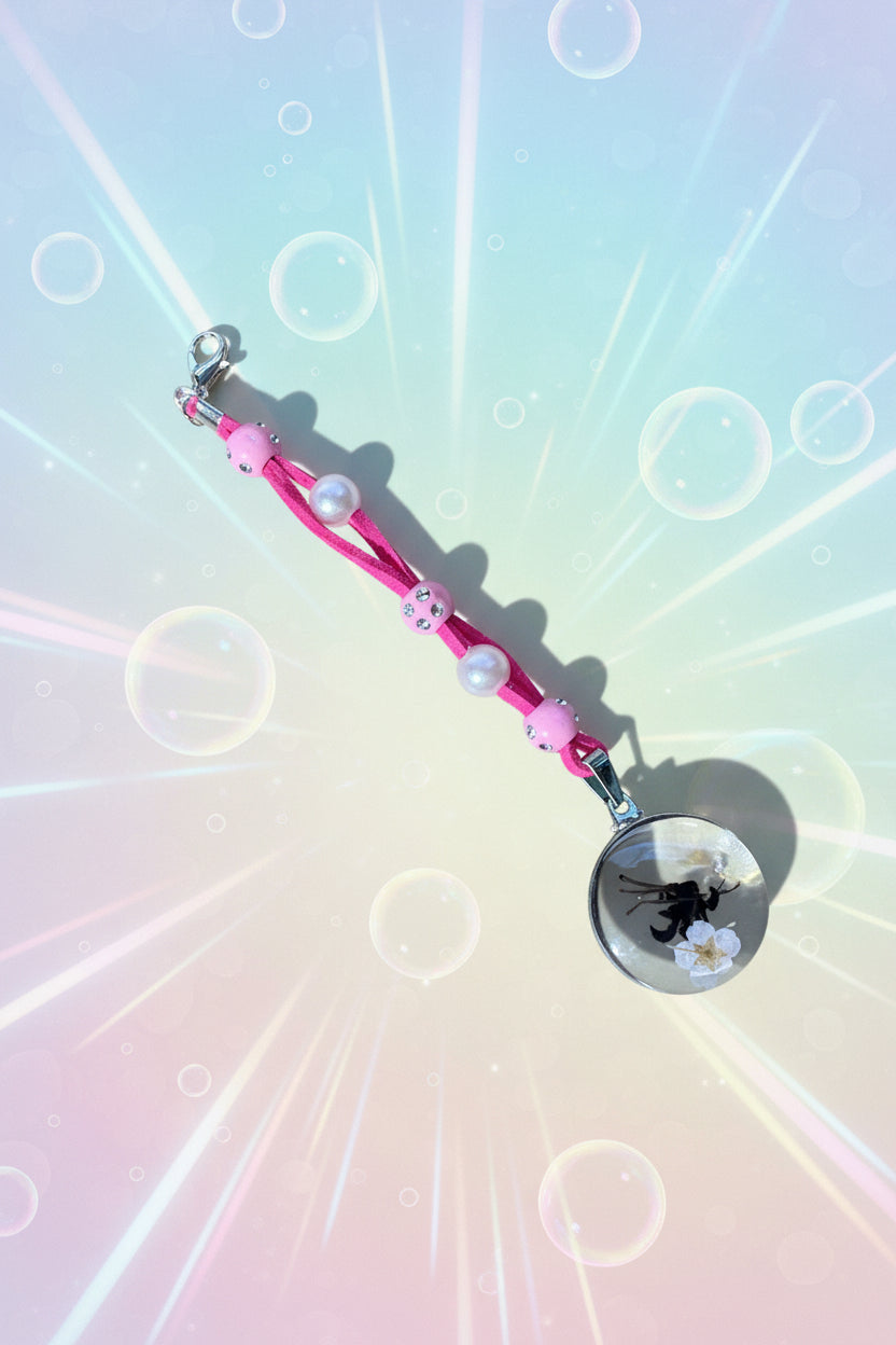 Add a touch of whimsy to your everyday carry with this beautiful handmade pink dangle charm. Each piece is lovingly crafted with sparkling pink beads and elegant white faux pearls, creating a delicate yet eye-catching accessory.