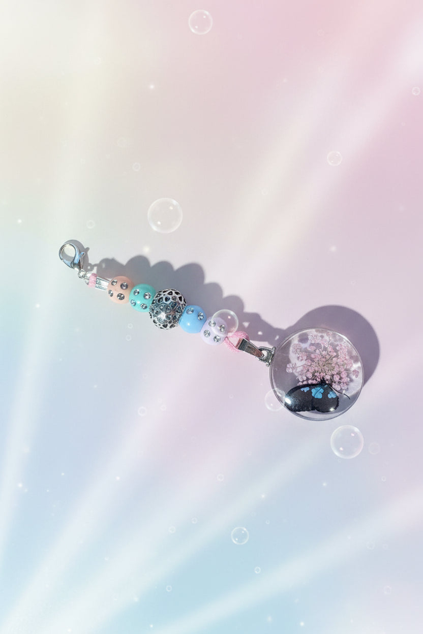 Add a touch of whimsy to your everyday carry with this beautiful handmade purple, blue, green and apricot dangle charm. Each piece is lovingly crafted with sparkling purple, blue, green and apricot beads and a cast floral bead creating a delicate yet eye-catching accessory.