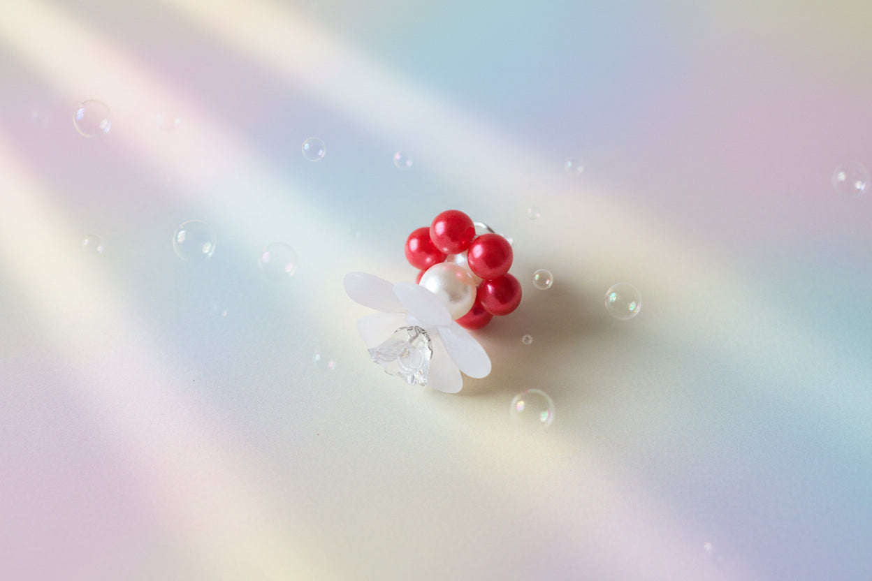 A stunning white flower bead takes centre stage, encircled by shimmering red pearlescent beads that create a mesmerising spinning effect. The soothing tactile motion helps with focus and stress relief while looking absolutely magical.