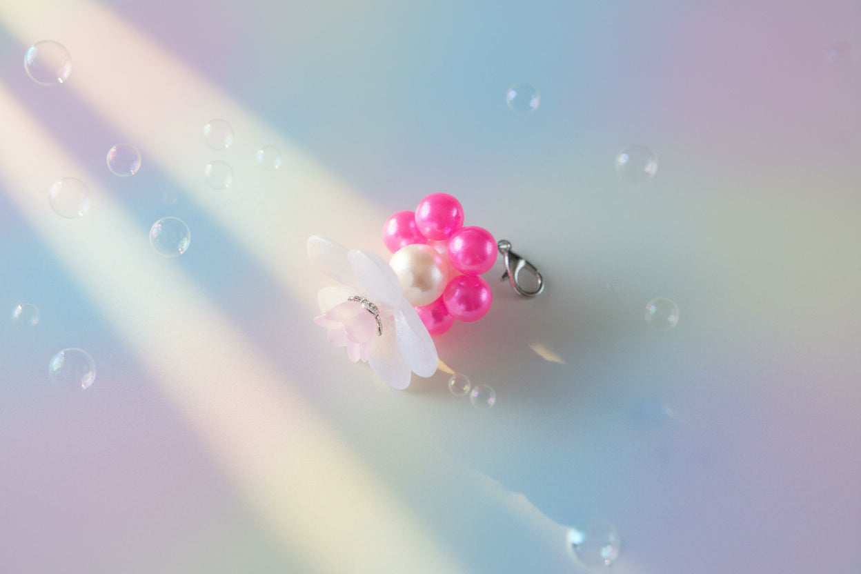 A stunning white flower bead takes centre stage, encircled by shimmering neon pink pearlescent beads that create a mesmerising spinning effect. The soothing tactile motion helps with focus and stress relief while looking absolutely magical.