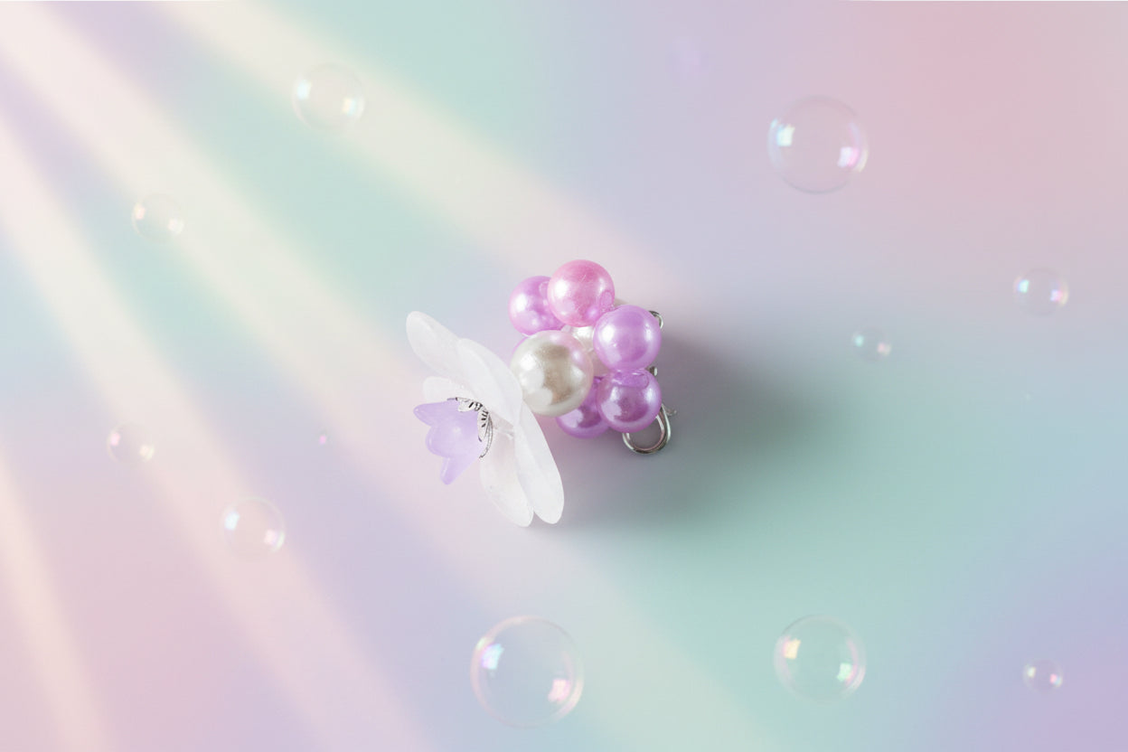 A stunning white flower bead takes centre stage, encircled by shimmering mauve pearlescent beads that create a mesmerising spinning effect. The soothing tactile motion helps with focus and stress relief while looking absolutely magical.