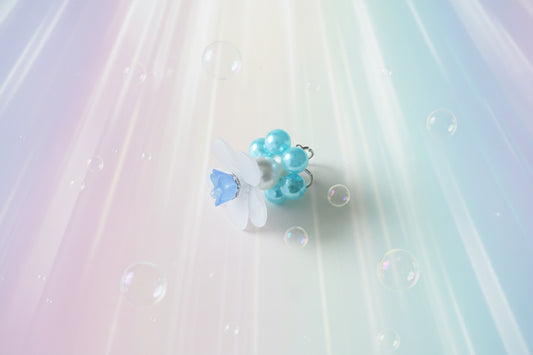 A stunning white flower bead takes centre stage, encircled by shimmering light blue pearlescent beads that create a mesmerising spinning effect. The soothing tactile motion helps with focus and stress relief while looking absolutely magical.