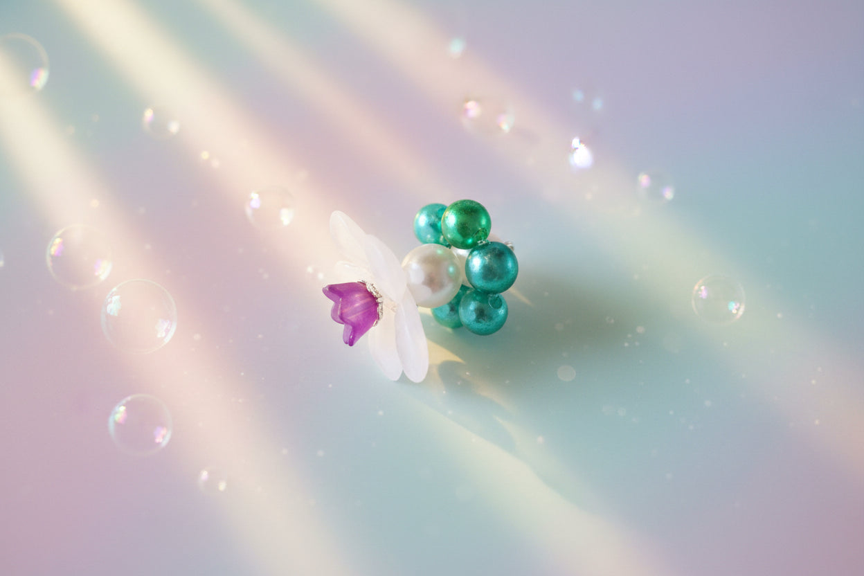 A stunning white flower bead takes centre stage, encircled by shimmering emerald green pearlescent beads that create a mesmerising spinning effect. The soothing tactile motion helps with focus and stress relief while looking absolutely magical.