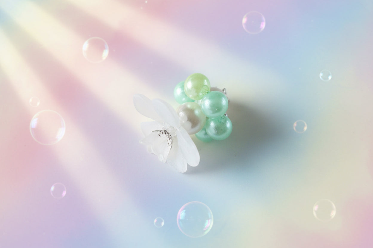 A stunning white flower bead takes centre stage, encircled by shimmering light green pearlescent beads that create a mesmerising spinning effect. The soothing tactile motion helps with focus and stress relief while looking absolutely magical.