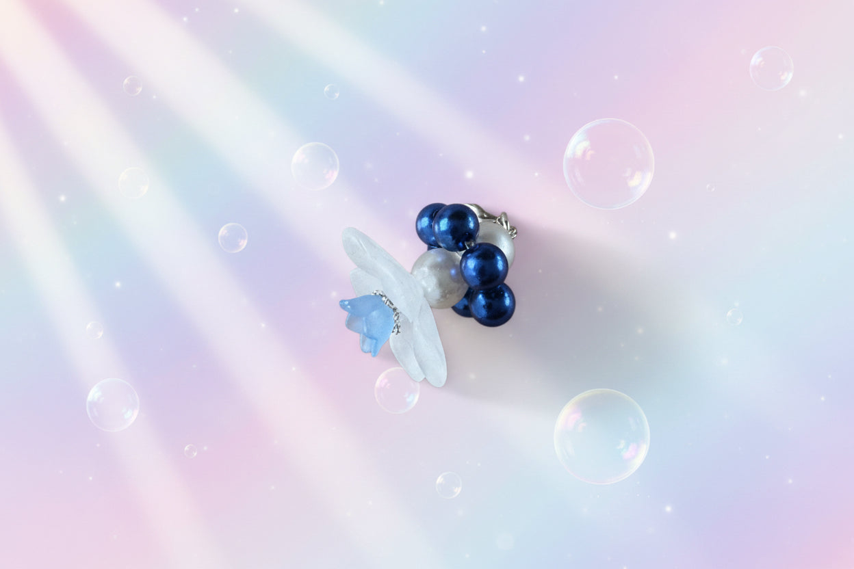 A stunning white flower bead takes centre stage, encircled by shimmering navy blue pearlescent beads that create a mesmerising spinning effect. The soothing tactile motion helps with focus and stress relief while looking absolutely magical.