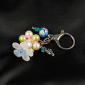 Pink and green pearlescent beads form a circlet beneath a large white flower bead creating a spinner fidget that has a chain with beads and lobster claw that can be clipped to your keychain.