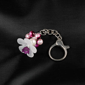 A stunning white flower bead takes center stage, encircled by shimmering fuchsia pearlescent beads that create a mesmerizing spinning effect. 
