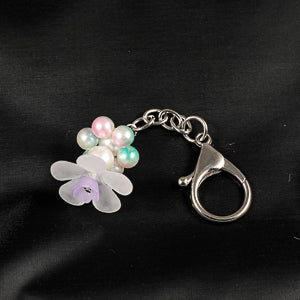 A stunning white flower bead takes center stage, encircled by shimmering multi colour pearlescent beads that create a mesmerizing spinning effect. 