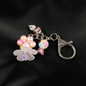 A stunning white flower bead takes center stage, encircled by shimmering pink pearlescent beads that create a mesmerizing spinning effect. The soothing tactile motion helps with focus and stress relief while looking absolutely magical.