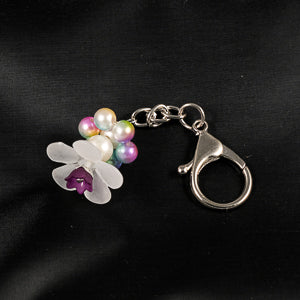 A stunning white flower bead takes center stage, encircled by shimmering purple, pink, blue and green pearlescent beads that create a mesmerizing spinning effect. The soothing tactile motion helps with focus and stress relief while looking absolutely magical.