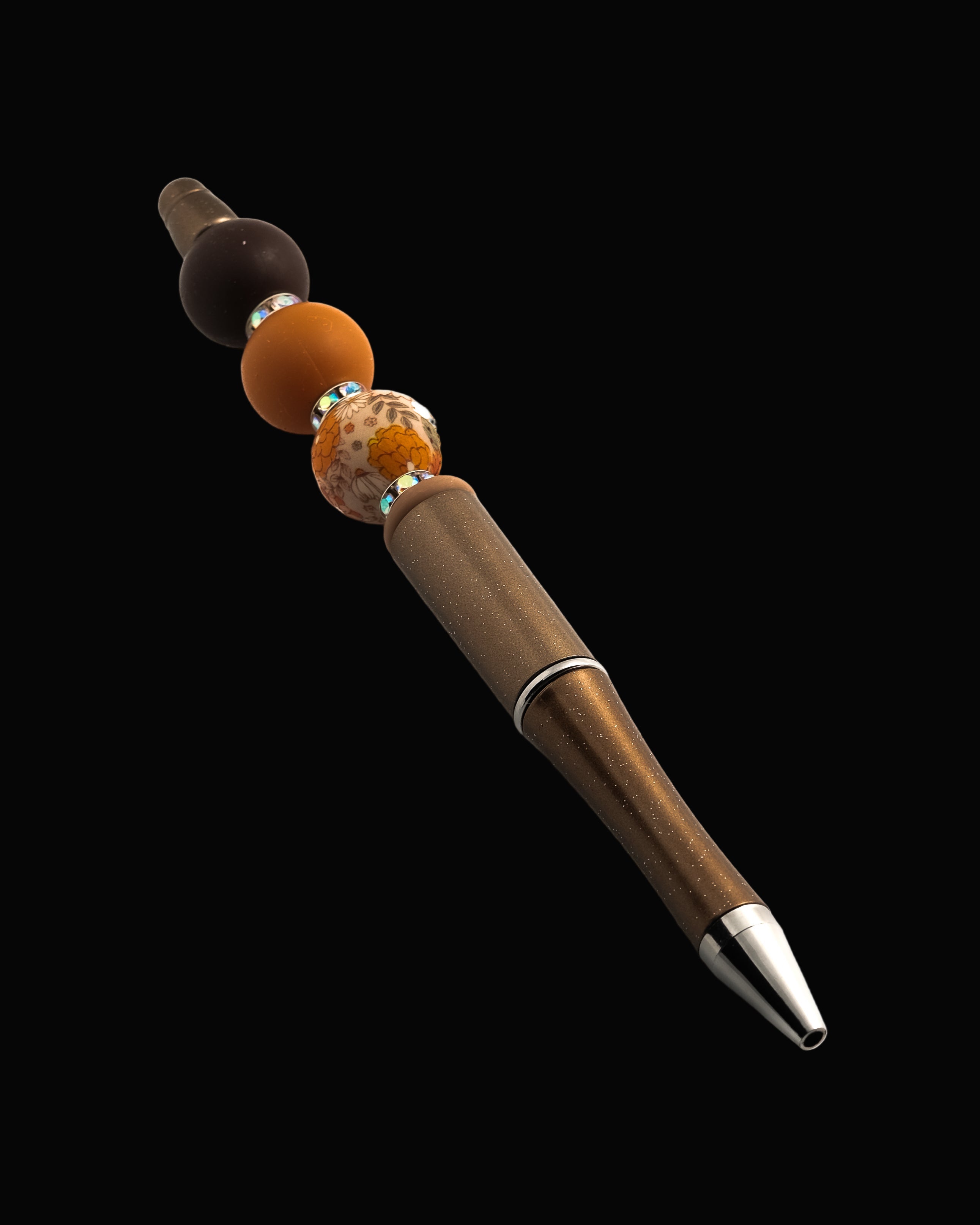 A bronze metallic pen with a brown bead, a terracotta bead, a floral bead, a fawn oval bead and sparkly Rondelles.