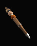 A bronze metallic pen with a terracotta bead, a floral round bead, an abstract bead, a fawn oval bead and sparkly Rondelles.
