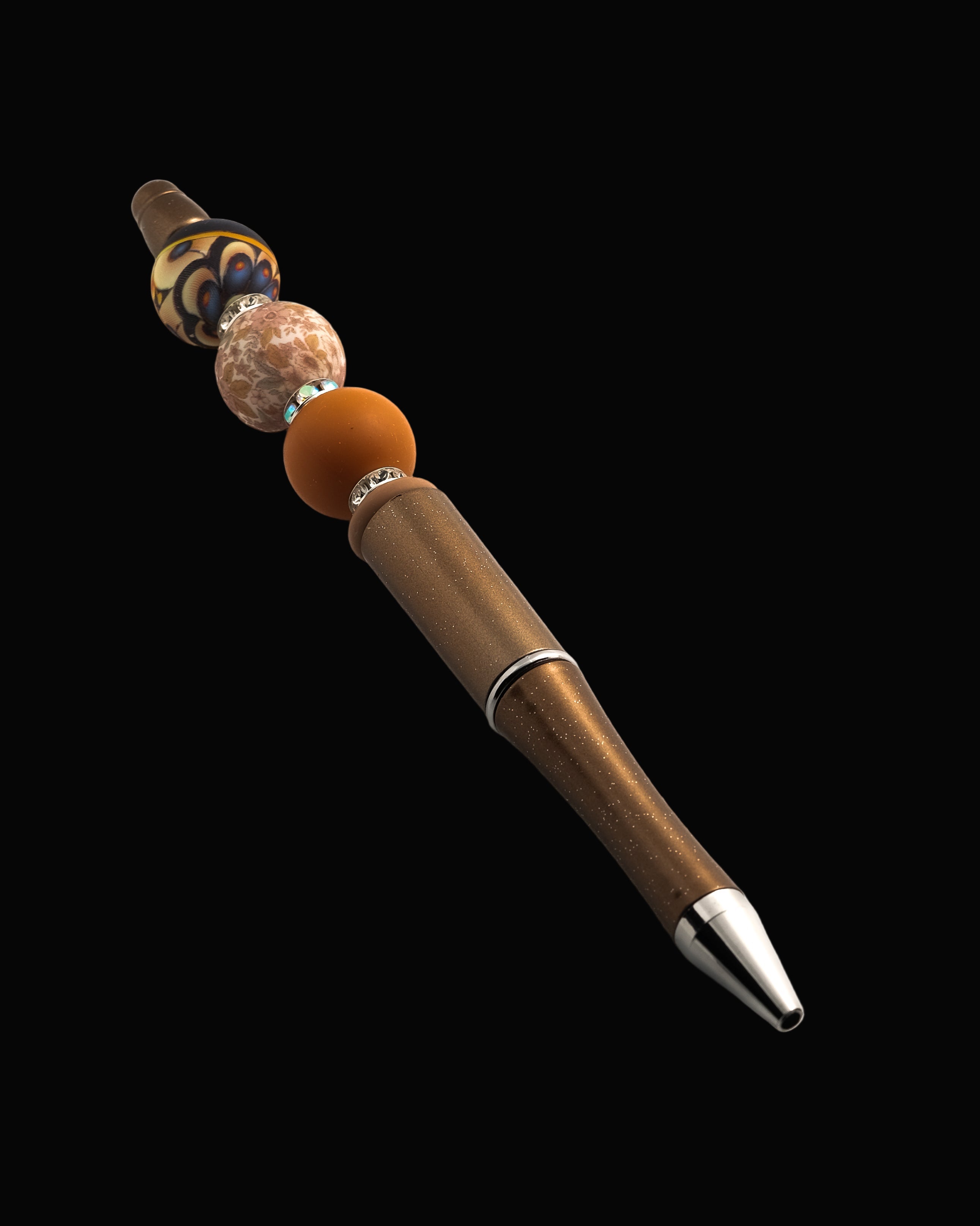 A bronze metallic pen with a terracotta bead, a floral round bead, an abstract bead, a fawn oval bead and sparkly Rondelles.