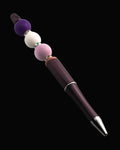 A purple metallic pen with a purple bead, a lilac round bead, a white bead, a fawn oval bead and sparkly Rondelles.