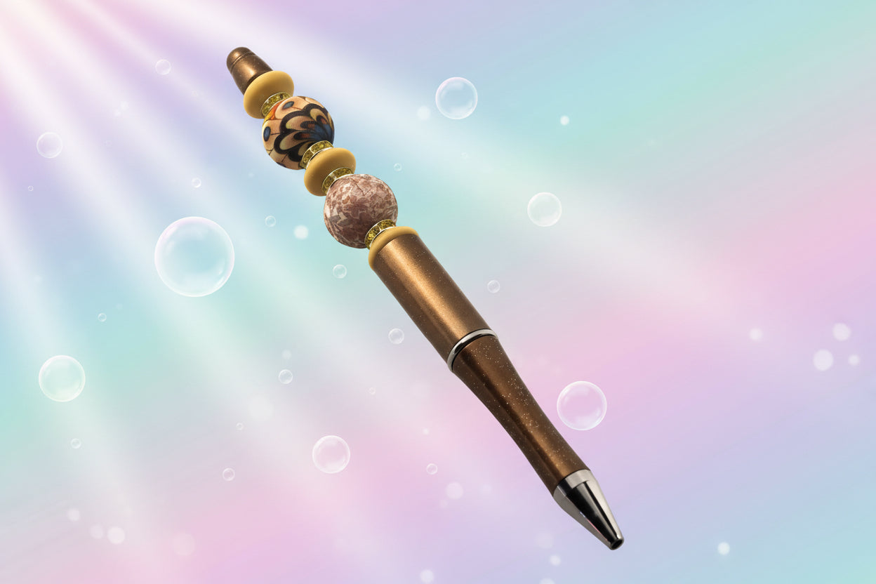 A bronze metallic pen with an abstract floral bead, a floral round bead, 3 fawn oval beads and yellow sparkly Rondelles.
