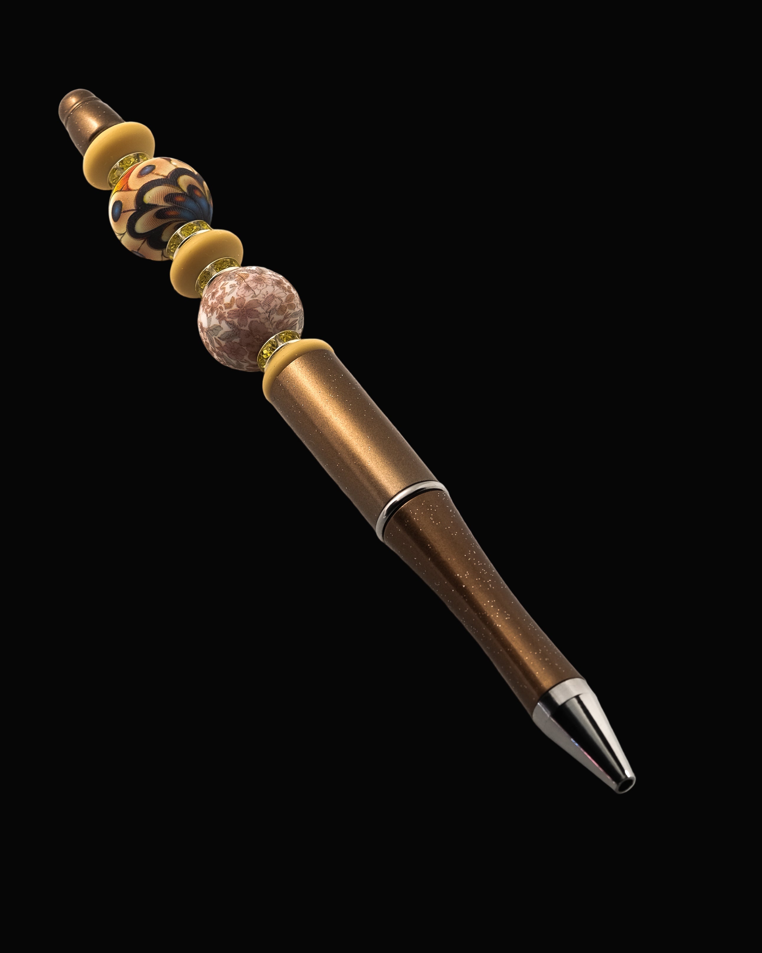 A bronze metallic pen with an abstract floral bead, a floral round bead, 3 fawn oval beads and yellow sparkly Rondelles.