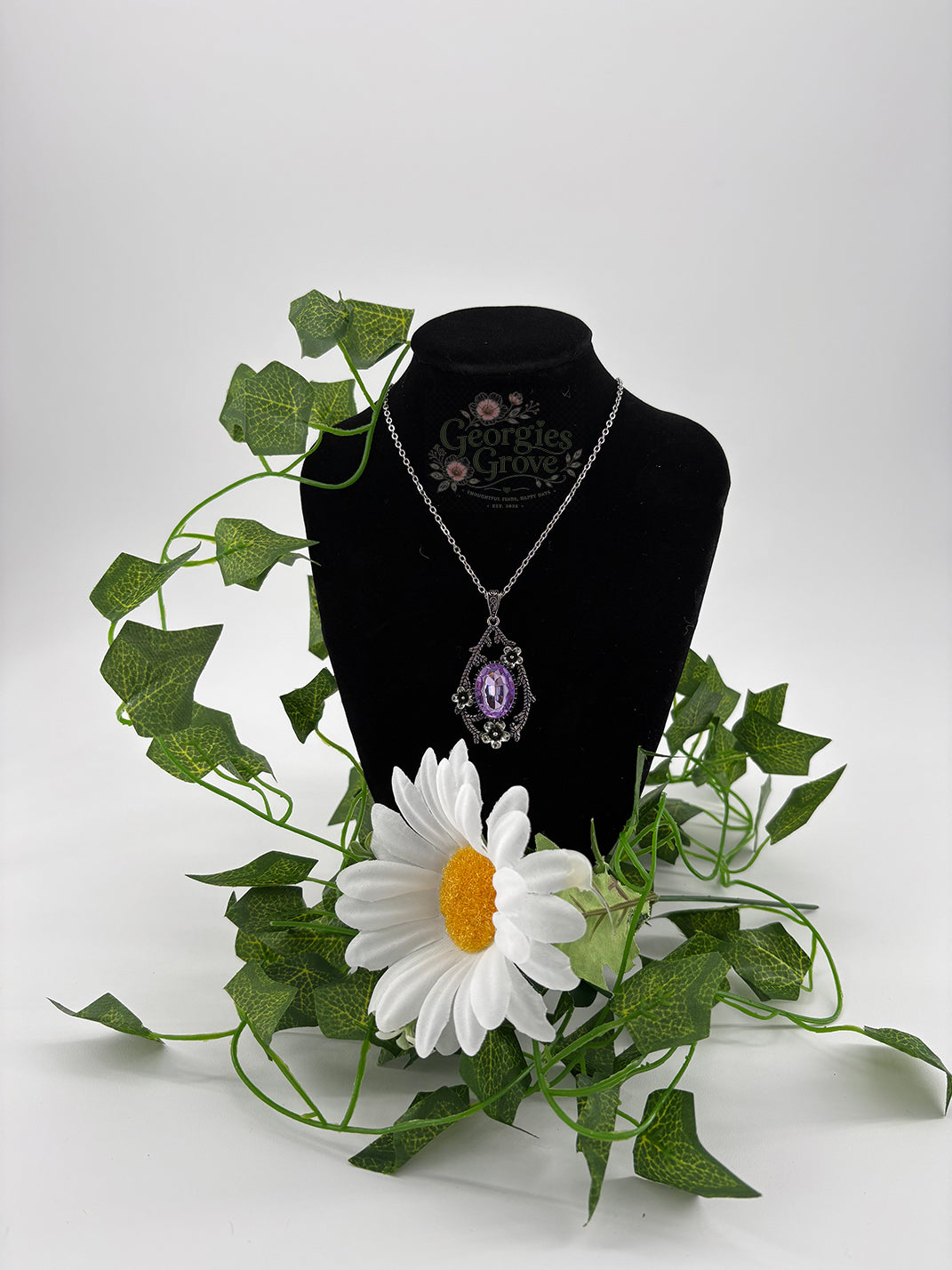 A teardrop shaped pendant with an oval stone surrounded by dainty flowers