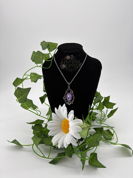 A teardrop shaped pendant with an oval stone surrounded by dainty flowers