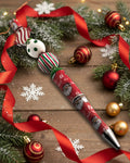 A red and white festive designed pen with wooden candy cane style beads
